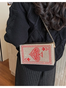 Detail of spade ace rhinestones evening bag with gold chain strap on a black sweater