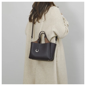 Detail of dark brown lychee leather handbag featuring T-logo and silver ring charm