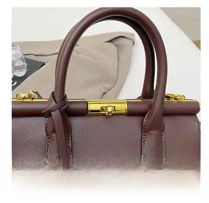 Close-up of premium dark brown leather handbag with luxury golden metal turn-lock closure