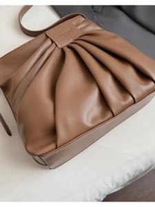 Close-up of the pleated texture and debossed logo on this brown matte leather bucket bag