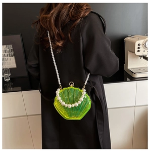 Detail of neon green shell-shaped acrylic bag with large pearl handle and long chain