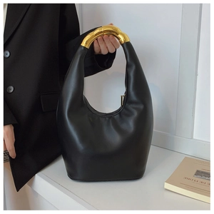 Dettaglio borsa in pelle nera con manico in metallo dorato scolpito e pieghe morbide