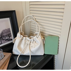 Detail of white drawstring bucket bag with star charm and pleated leather texture