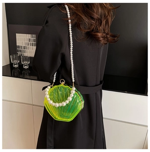 Detail of neon green acrylic shell clutch with pearl handle on black coat background