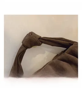 Close-up of brown suede cloud bag featuring a unique knotted handle design details