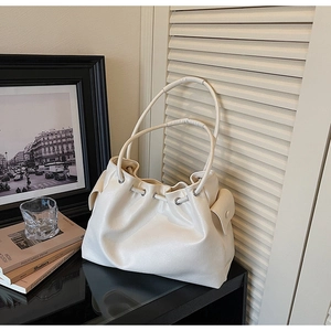 Close-up of beige leather bucket tote bag with drawstring closure and side flap pockets