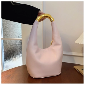 Dettaglio borsa hobo in pelle rosa chiaro con manico scultoreo dorato e cerniera