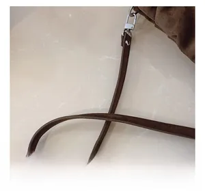 Macro shot of dark brown suede bag featuring a slim shoulder strap and silver metal buckle