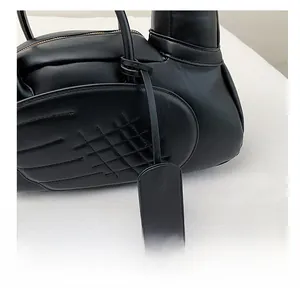 Détail du sac en cuir noir avec coutures en forme d'ailes et étiquette décorative