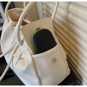 Detail of a black pebbled leather pouch with green zipper tucked in a white tote bag