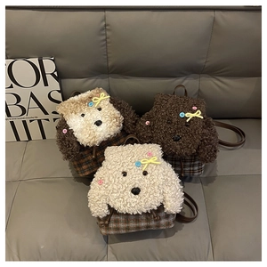 Dettaglio di tre zaini in peluche a forma di orso con base a scacchi e fiocchi colorati