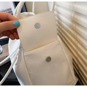 Detailed view of cream bucket bag showing smooth faux leather texture and magnetic snap closure