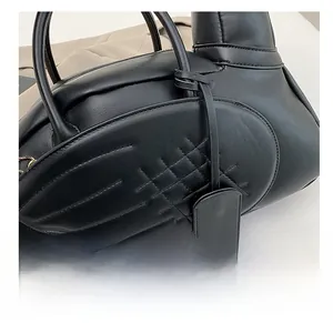 Détail d'un sac à main noir en similicuir montrant le design d'aile et les surpiqûres
