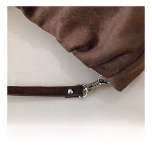 Detailed close-up of silver metal hook and strap connection on brown suede handbag
