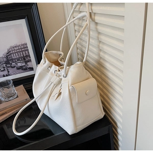 Detail view of a creamy white drawstring bucket bag with a side pocket and soft PU leather