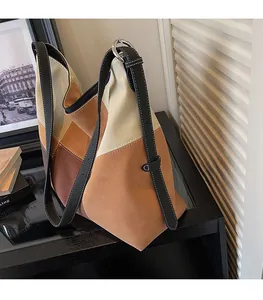 Detail of color-block suede hobo bag with contrast stitching on leather shoulder strap