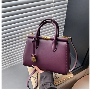Detail of dark purple leather tote bag showing golden padlock and handle textures