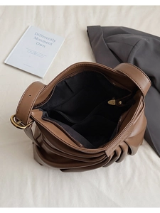 Detail view of large interior capacity and organizational pockets of brown pleated tote bag