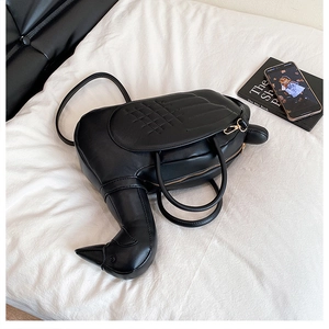 Détail d'un sac à main noir en forme de canard avec ailes matelassées et zip doré brillant