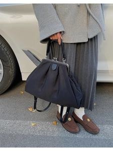 Détail d'un sac à main plissé noir avec fermoir métallique rétro et poignée