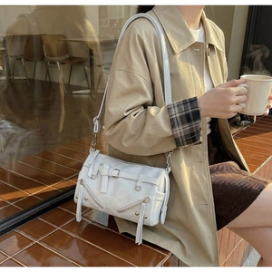 Detail of white vintage biker style bag with metallic zippers and decorative rivets