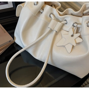 Detail of off-white leather bucket bag with drawstring closure and star pendant charm