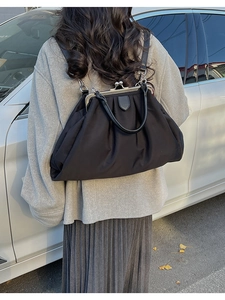 Détail du sac plissé noir avec fermoir métallique vintage et bretelles de sac à dos