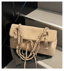 Dettaglio borsa scamosciata marrone chiaro con borchie argentate e tracolla intrecciata