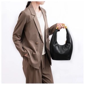 Dettaglio del manico scultoreo dorato su una borsa hobo nera dal design minimalista