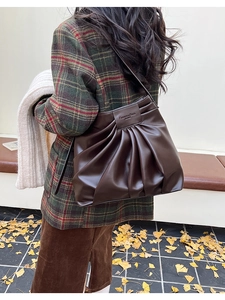 Detail view of deep brown pleated bucket bag worn with a stylish autumn plaid blazer