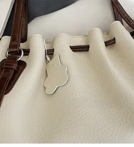Close-up of off-white lychee texture faux leather bucket bag with brown drawstrings