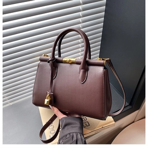 Detail of premium brown leather handbag with gold twist lock and elegant top handle