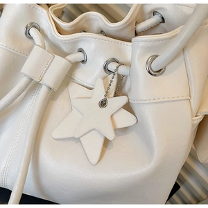 Close-up of white leather bucket bag featuring drawstring closure and star pendant