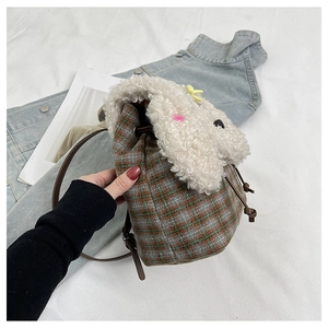 Dettaglio borsa a secchiello a scacchi in peluche con patta in pile e tracolla in pelle