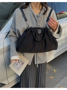 Détail d'un sac à cadre plissé noir avec fermoir en métal argenté et lanières