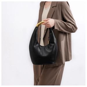 Dettaglio borsa a mano in pelle nera minimalista con elegante manico in metallo dorato
