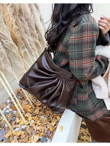Detail of dark brown pleated bucket bag with vintage autumn vibes on a model