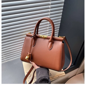 Detail of caramel leather handbag with gold lock and textured finish in natural light