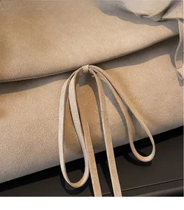 Dettaglio ravvicinato della borsa tote in pelle scamosciata beige con nodo e trama morbida