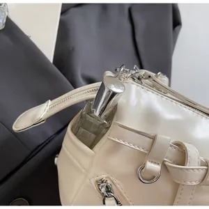 Detail view of cream shoulder bag showing functional side pocket with perfume bottle