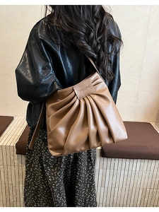 Detail of caramel pleated bucket bag with leather brand patch and pleated texture