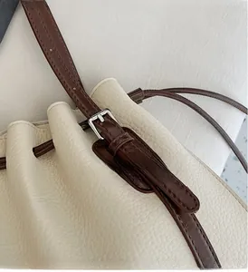 Detail of silver metal adjustment buckle on beige lychee leather strap for tote bag
