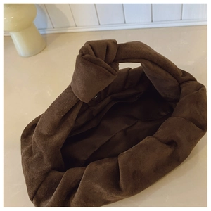 Detail of coffee brown pleated suede dumpling bag with unique knotted top handle