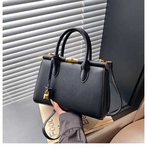 Close-up of black PU leather handbag with gold metal lock and elegant curved handle