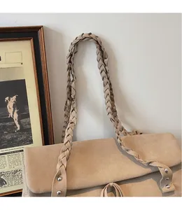Dettaglio della tracolla intrecciata a mano e texture scamosciata della borsa