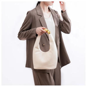 Dettaglio borsa hobo beige con manico ad arco metallico dorato per un look moderno