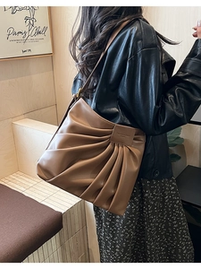 Macro detail of brown pleated leather bucket bag featuring unique accordion design texture