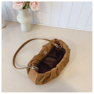 Detail view of brown ruched cloud bag with soft suede texture and magnetic buckle