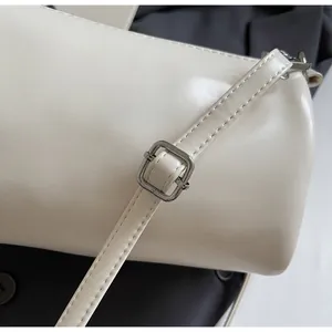 Detail of adjustable shoulder strap and silver metal buckle on a beige cylinder bag