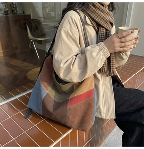 Detail of color-block patchwork tote bag in suede fabric against outdoor brick background